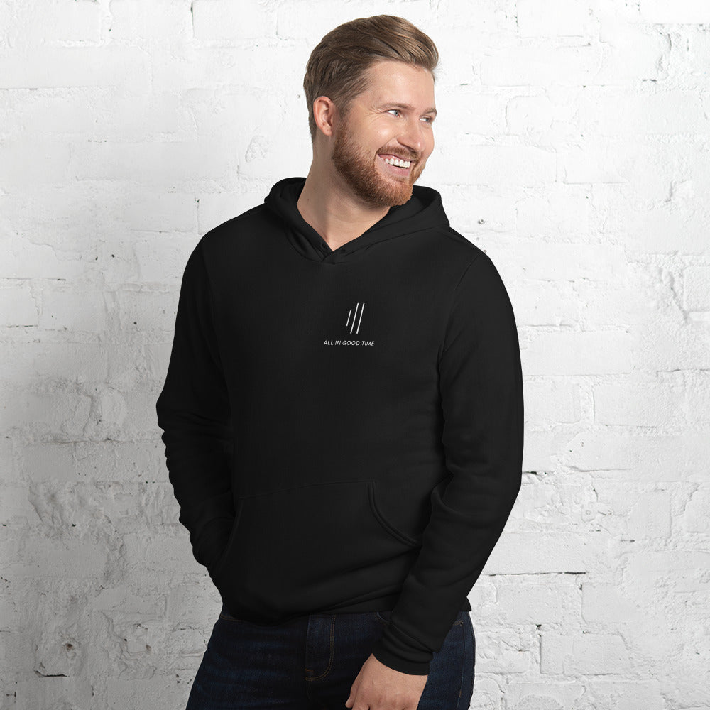 Man wearing black drummer hoodie by Cowbell & Groove, minimalist chest print with 'All in Good Time' and groove bar logo reinterpretation