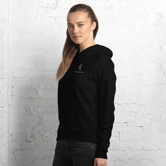 Woman wearing black drummer hoodie by Cowbell & Groove, side pose with minimalist groove bar logo and 'All in Good Time' visible on chest