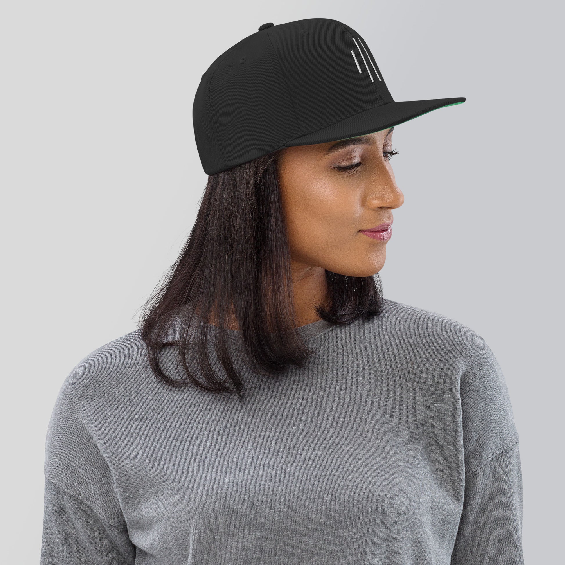 Side view of woman wearing Cowbell & Groove drummer snapback hat, black cap with embroidered groove bar logo — stylish gift for percussionists